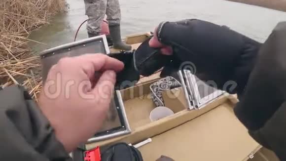 垂钓者在船上戴上钓鱼手套视频的预览图