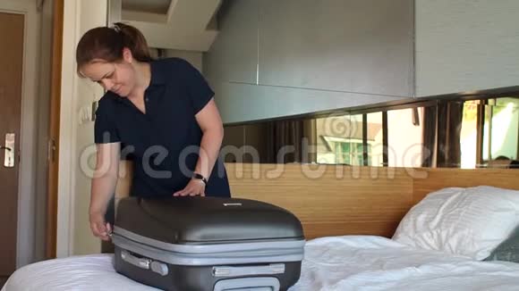 女人在旅馆的床上解开手提箱把行李装在手提箱里视频的预览图