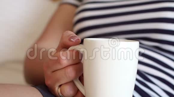 一个躺在床上的女孩手中的白色咖啡杯的特写视频的预览图
