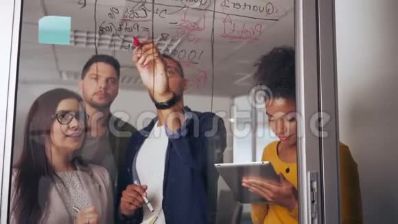男企业家和他的同事在玻璃板上讨论商业想法和计划视频的预览图