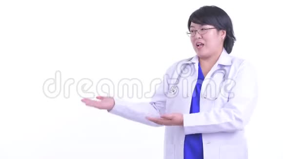 快乐超重的亚洲女医生一边说话一边显示视频的预览图