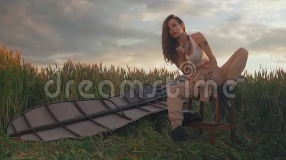 漂亮的女人坐在田里背上有翅膀手里拿着烟飞行后休息视频的预览图