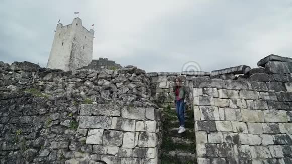 在一座高塔的背景下可爱的女孩正走下一座古老堡垒的石阶视频的预览图