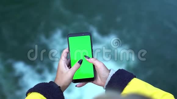 用智能手机拍摄黄色外套的年轻旅游女孩在瀑布自然移动生态旅游中的双手特写视频的预览图