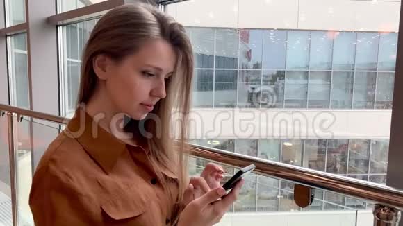 办公室内微笑的年轻商务女性浏览智能手机视频的预览图