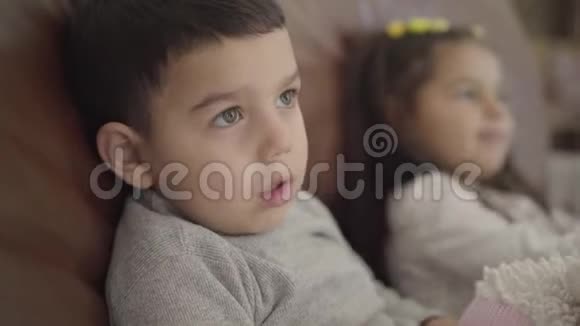 一个中东小男孩和他妹妹坐在教练旁边的特写脸在舒适的家中度过儿童之夜视频的预览图