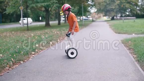 一个戴着消防员头盔的男孩沿着跑道骑着高速公路视频的预览图