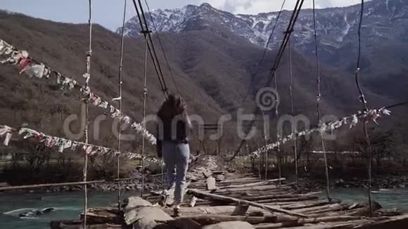 女孩偷偷地沿着一座被毁的悬索桥越过一条干净的山河背面视频的预览图