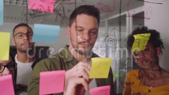 创意商人在玻璃墙上用黏糊糊的纸条写计划同事在办公室待命视频的预览图