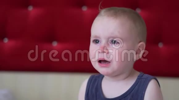 小男孩金发的打哈欠和哭泣坐在房间的床上慢动作视频的预览图