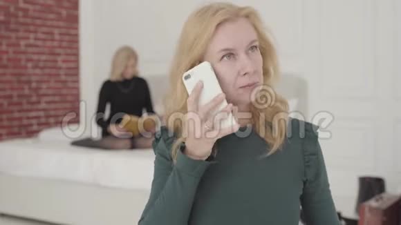 一个有魅力的白人成熟女人在家打电话的画像她的金发朋友坐在床上视频的预览图