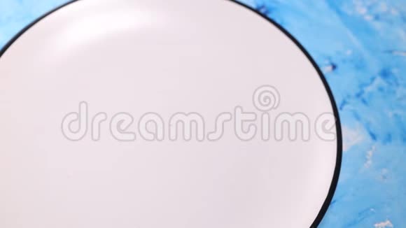 特写一位女士的手在蓝色背景的白色盘子里放着新鲜的华夫饼视频的预览图