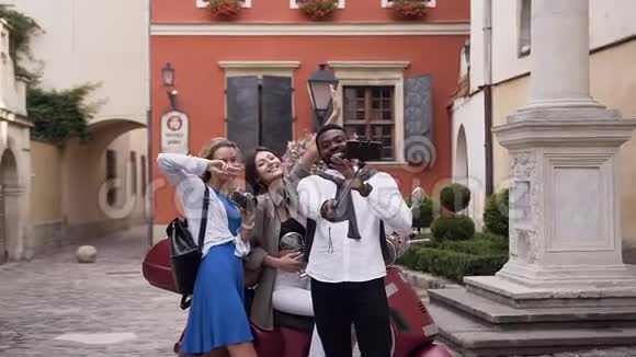 吸引人的快乐混合种族朋友在城市建筑的背景下用滑稽的面孔自拍视频的预览图