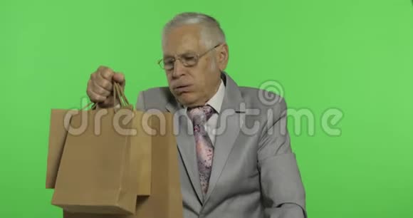 无聊的老人提着购物袋购物后穿正装的老人视频的预览图