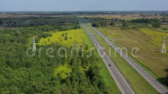 在田野和森林之间经过的双车道公路的鸟瞰图视频的预览图