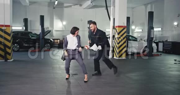 时尚的经理女人穿着西装一个男机修工在一台现代的照相机前兴奋地跳舞视频的预览图