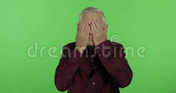 老人把脸藏在他的手里进行间谍活动英俊的老人铬键视频的预览图