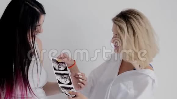母亲和怀孕的女儿说话和看超声照片视频的预览图