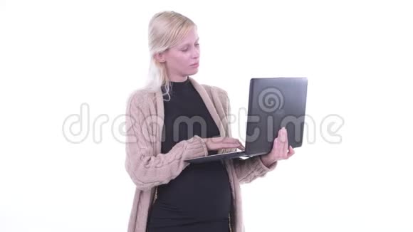快乐的年轻金发孕妇一边用笔记本电脑一边思考视频的预览图