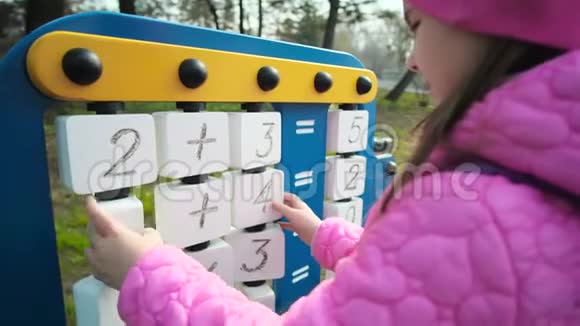 一个女学生在凉爽的天气在学校场地玩耍孩子解数学方程式逻辑练习视频的预览图