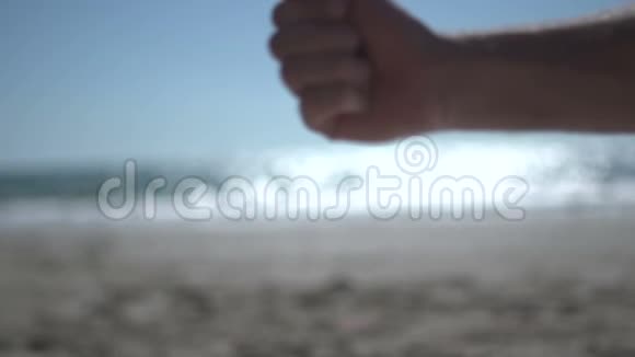 在海滩上近距离用近人的手射击拿着沙滩沙慢慢地打开视频的预览图