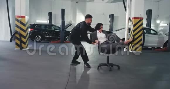 帅哥和他的女经理在一家汽车服务中心玩他们在椅子上跳舞视频的预览图