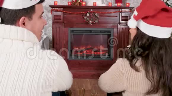 圣诞前夜一对放松的夫妇在壁炉前享用一杯香槟视频的预览图