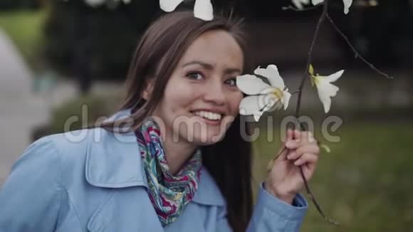 美丽的女孩微笑着审视着玉兰花嗅着它们视频的预览图