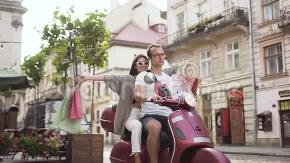 可爱的快乐的年轻女士戴着时尚的太阳镜和她的男朋友一起骑着滑板车穿过她的男朋友视频的预览图