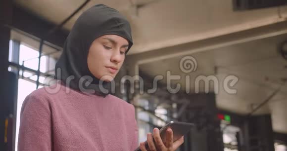用平板电脑拍摄年轻运动女性头巾的特写肖像并在健身房中显示绿色彩色钥匙屏幕视频的预览图