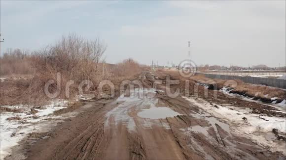 俄罗斯的春天肮脏的春路泥土覆盖雪融化在路边在春天的季节创造了水坑肮脏的雪视频的预览图