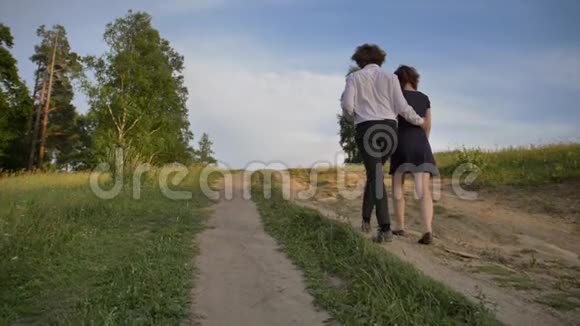 两个年轻人一个男人和一个女孩拥抱着爬山沿着公园里的小路视频的预览图