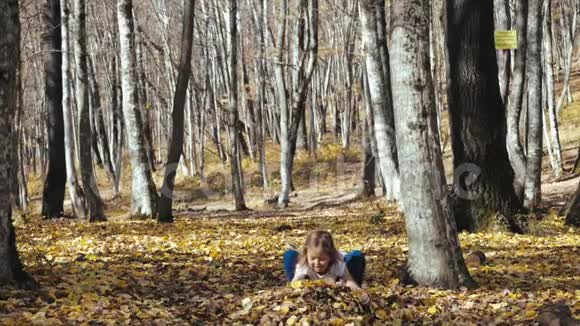 快乐的小女孩在秋天的森林里玩得很开心视频的预览图