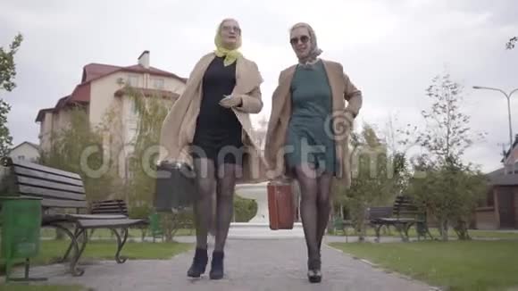 两个成熟的白人女性朋友穿着优雅的衣服和太阳镜在城市公园散步和交谈魅力视频的预览图