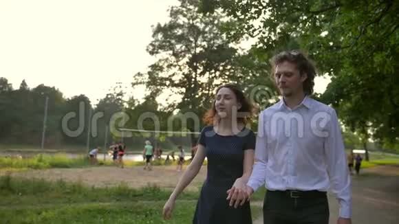 正面肖像的年轻夫妇男人和女人牵着手走在一条小径上的森林视频的预览图
