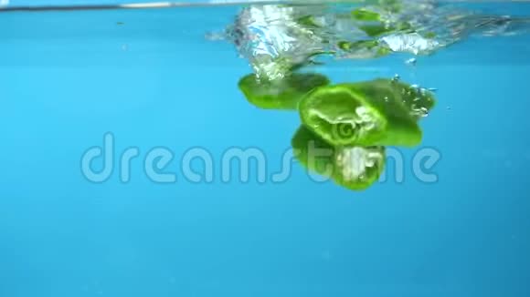 切片的青辣椒落入水中蓝色背景视频的预览图
