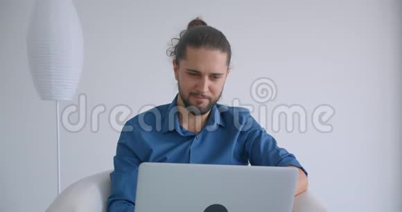有马尾辫的进步自由职业者手提电脑坐在舒适而轻盈的办公室里微笑着视频的预览图