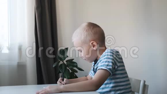 小男孩孩子坐在家里的桌子旁画画妈妈亲吻拥抱他视频的预览图