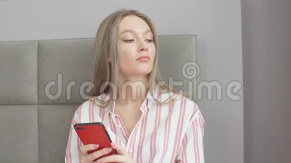 穿着漂亮睡衣的年轻女孩在酒店房间的早期使用电话视频的预览图