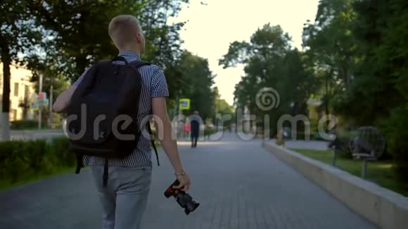 一位学生摄影师正走在他身后的城市街道上视频的预览图