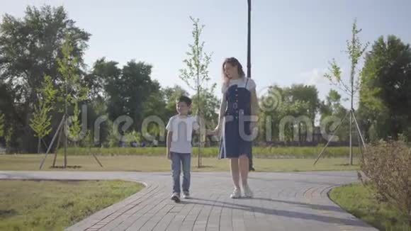姐姐在夏天公园里和弟弟牵手散步淘气的男孩跑了女孩跑了视频的预览图