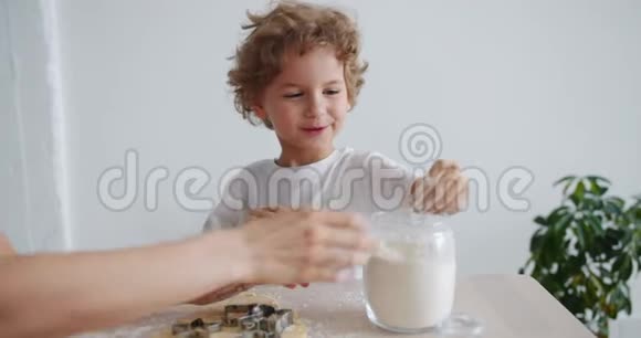 可爱的男孩帮妈妈烤饼干在厨房里玩面粉视频的预览图