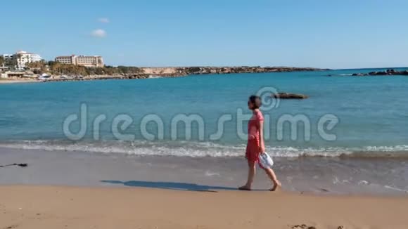 年轻迷人的孤独女孩走在海边的沙滩上漂亮的白种人女人穿着红色的衣服在海边散步裸舞视频的预览图