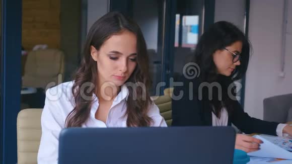女员工在办公室工作漂亮的眼镜女商人在现代办公室的笔记本电脑上工作视频的预览图