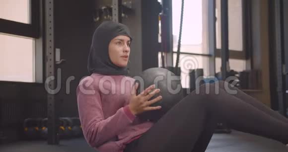 年轻坚定的阿拉伯运动女性戴着头巾在室内健身房锻炼时的特写镜头视频的预览图