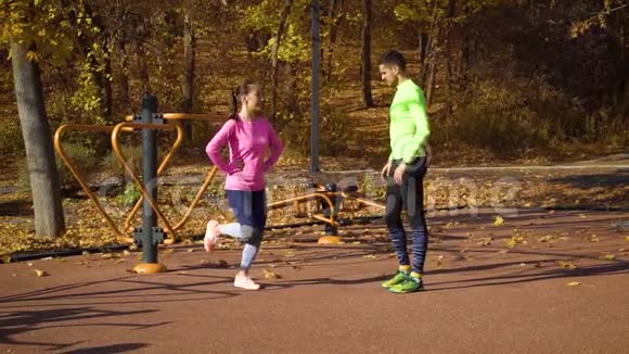 年轻夫妇在秋季公园的运动场上热身视频的预览图