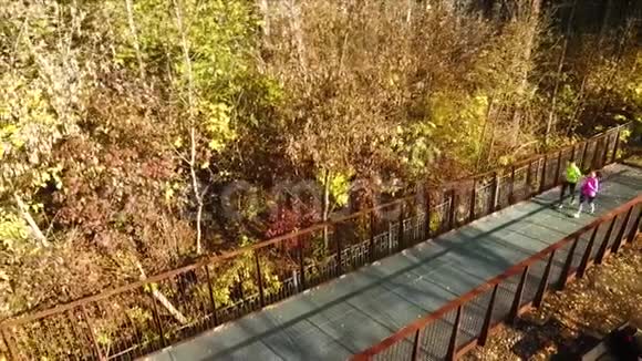 秋公园桥上慢跑的年轻情侣视频的预览图
