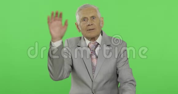年长的商人用手对着镜头挥手穿着正式服装的老人视频的预览图