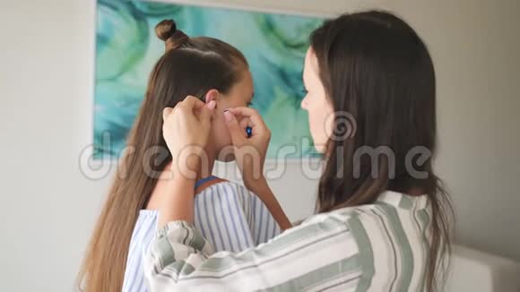 女人帮女儿给十几岁的孩子戴耳环视频的预览图