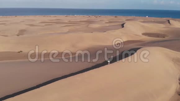 日落时分一个穿着夏装的年轻白种人女孩沿着沙漠的边缘奔跑马斯帕洛马斯加那利视频的预览图